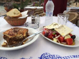 Moussaka och grekisk sallad på ett tavernabord i Grekland